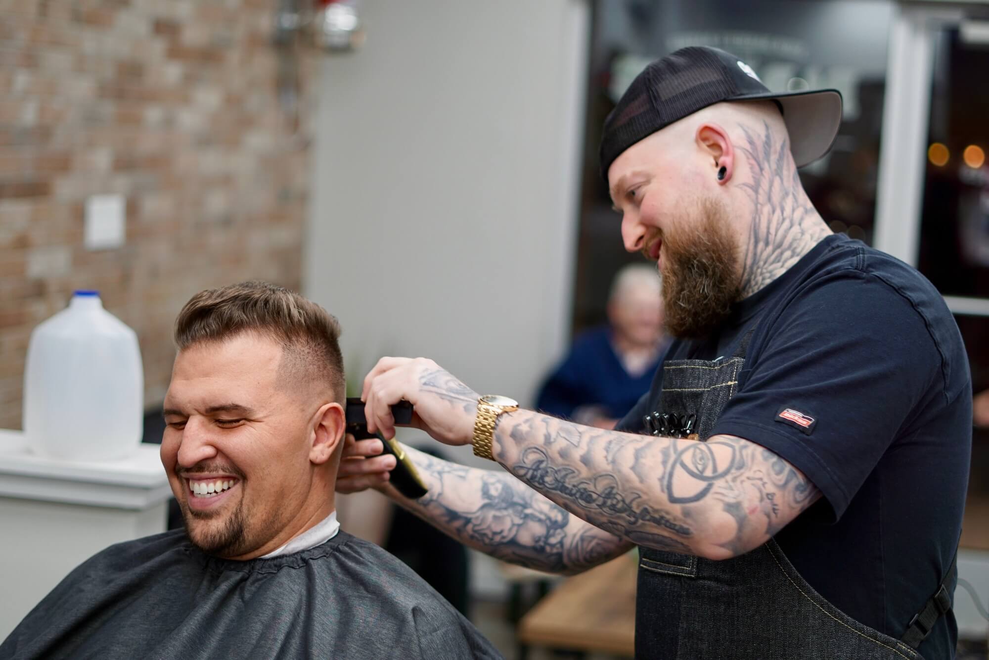 a man cutting another man's hair with a smile